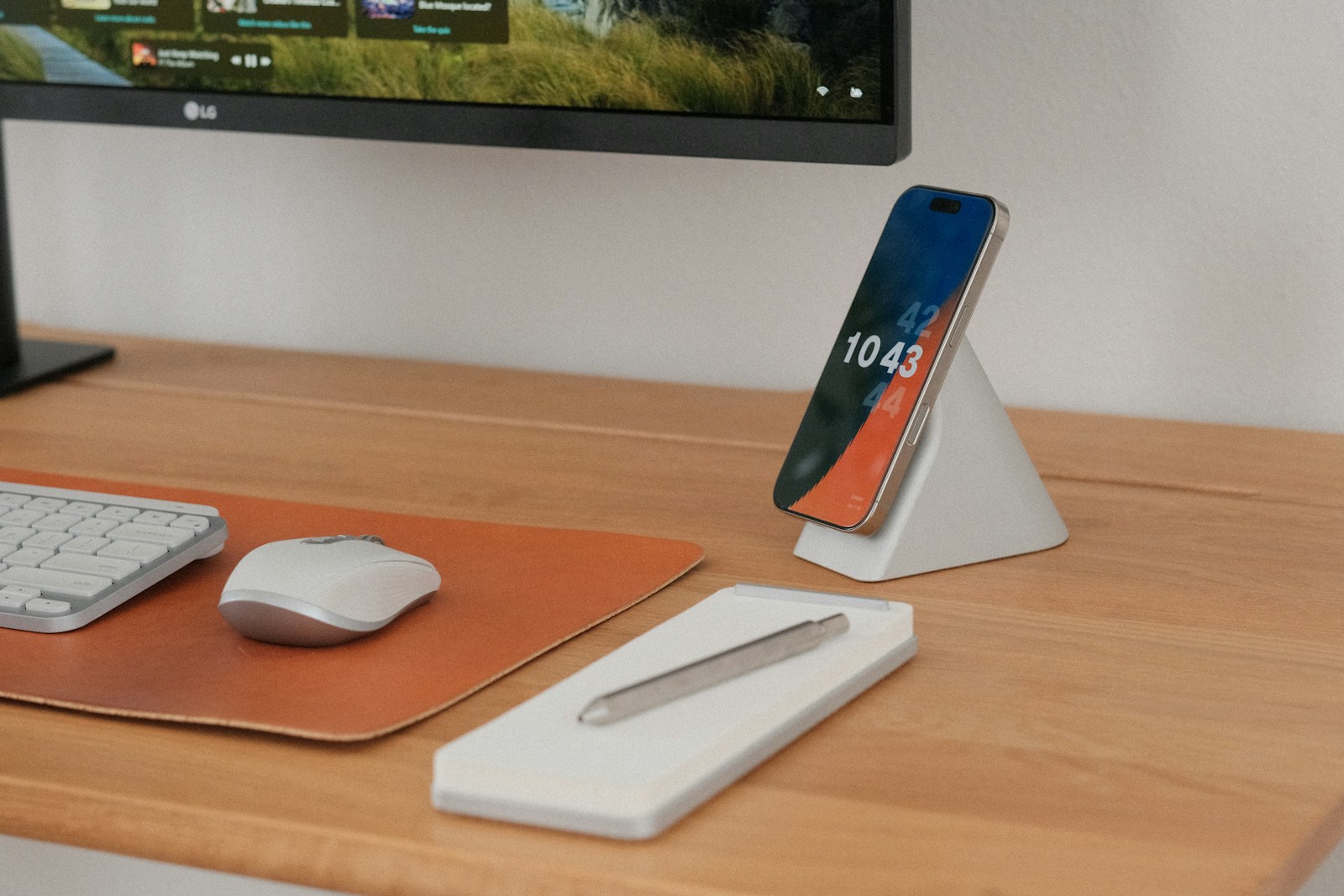 Phone and accessories neatly arranged on a wooden desk.